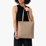 Stone North/South | Model holding structured wide tote bag with overlapping panels and crossbody strap