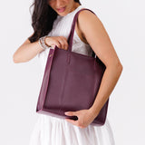 Lollipop North/South | Model holding structured large tote bag with overlapping panels and crossbody strap