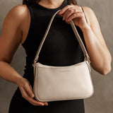 Bone Small | Model holding petite bean shaped shoulder bag with a zipper closure