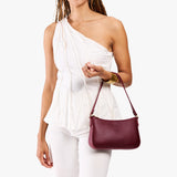 Cabernet Small | Model carrying petite bean shaped shoulder bag with a zipper closure