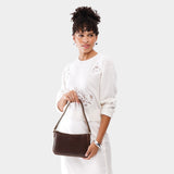 Chocolate Brown Small | Model holding petite bean shaped shoulder bag with a zipper closure