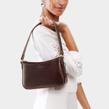 Chocolate Brown Small | Model holding petite bean shaped shoulder bag with a zipper closure