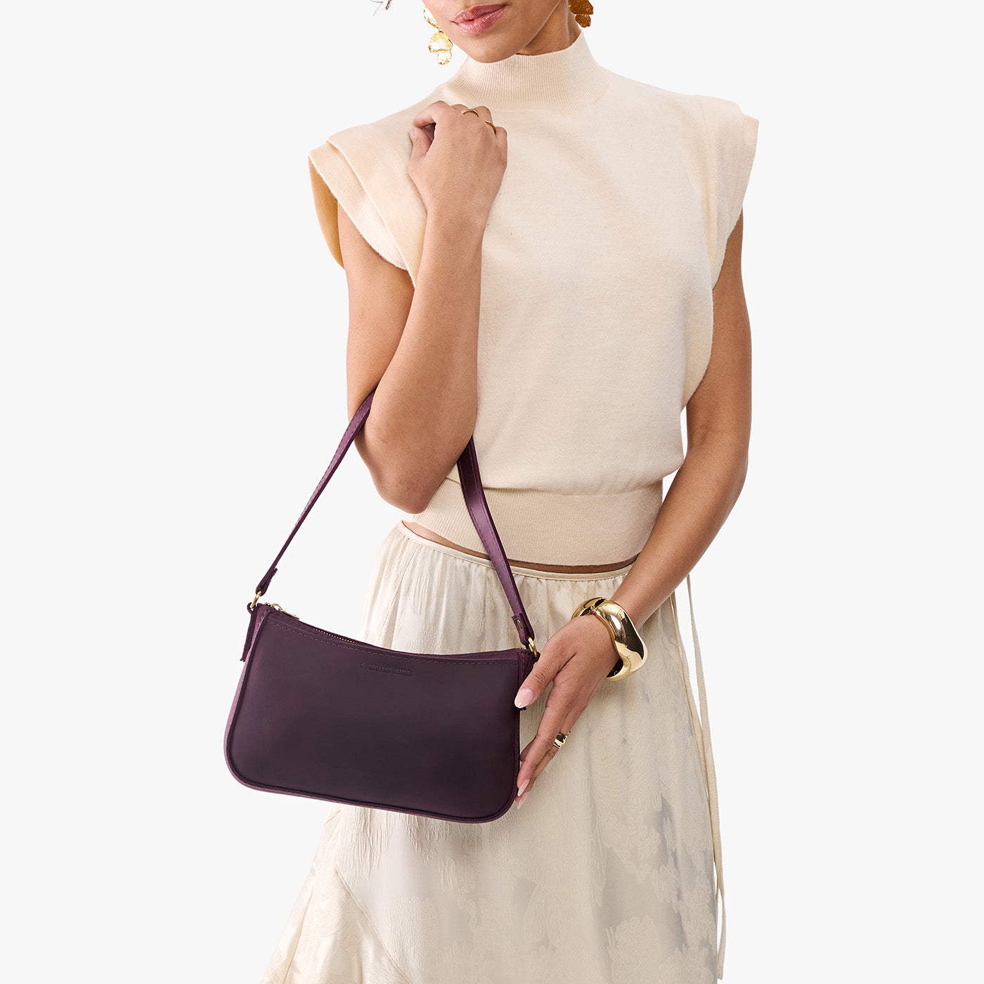 Larkspur | Model carrying petite bean shaped shoulder bag with a zipper closure