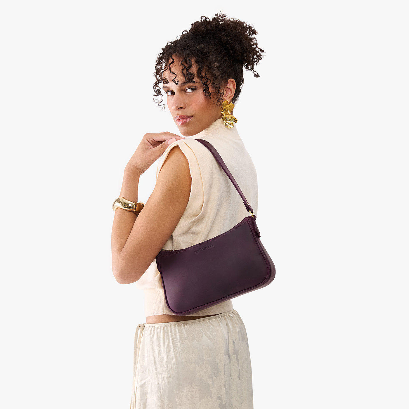 Larkspur | Model carrying petite bean shaped shoulder bag with a zipper closure