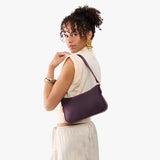 Larkspur | Model carrying petite bean shaped shoulder bag with a zipper closure