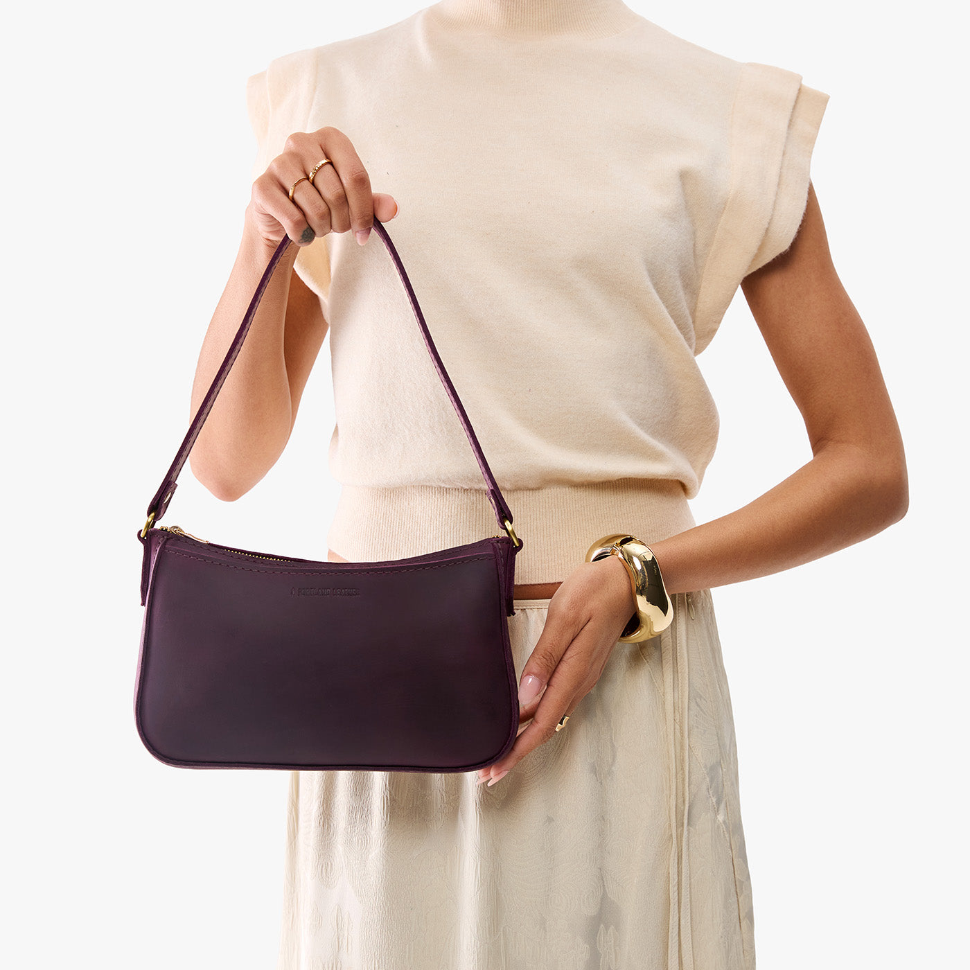 Larkspur | Model carrying petite bean shaped shoulder bag with a zipper closure