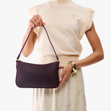 Larkspur | Model carrying petite bean shaped shoulder bag with a zipper closure