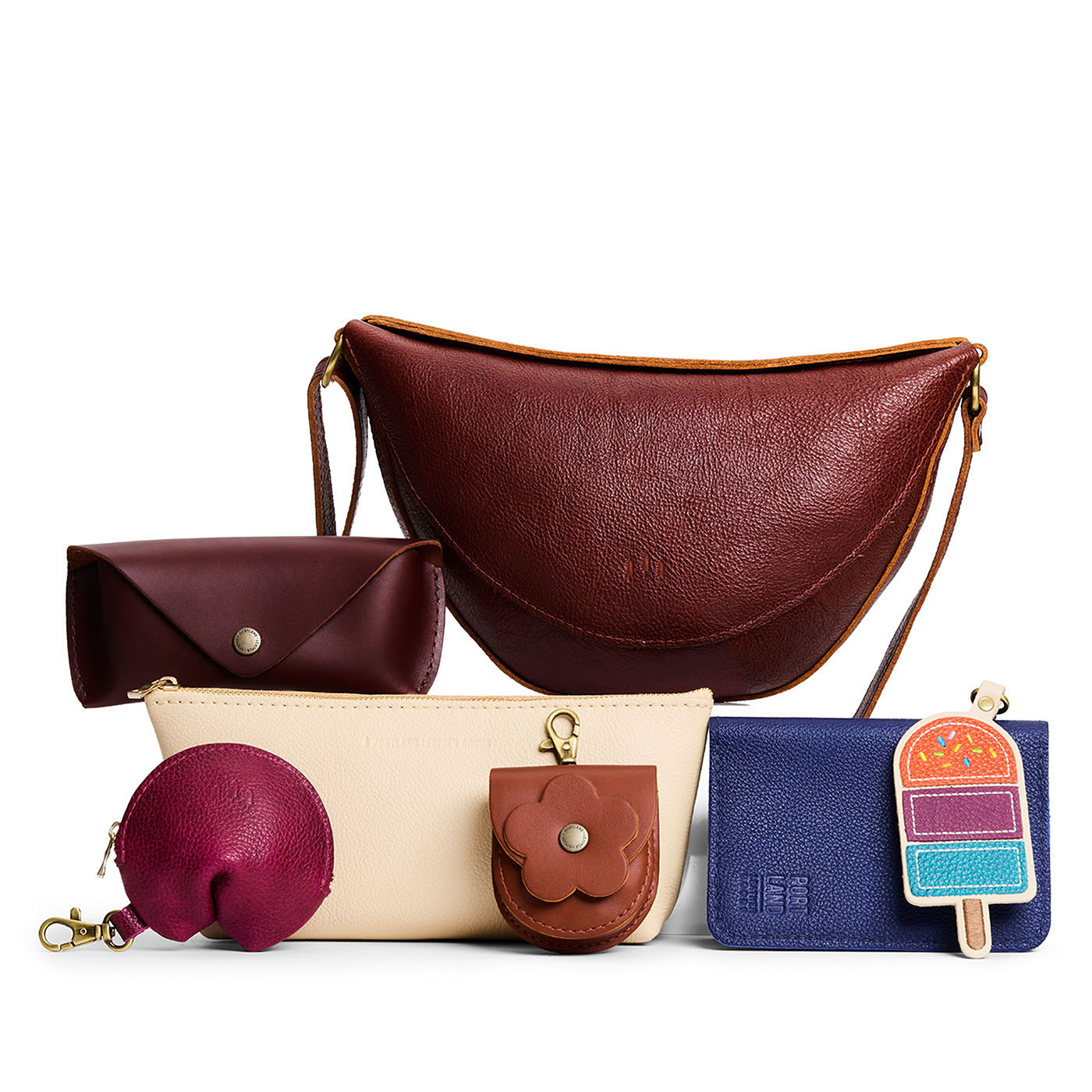 All Color: 1 Koala + 6 Items | Koala Sling Bag in Nutmeg next to Sunglasses Case, Utility Bag, Fortune Cookie Keychain, Petunia Pouch, Modern Leather Passport Holder, and Popsicle Keychain