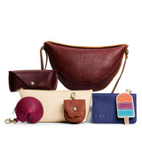 All Color: 1 Koala + 6 Items | Koala Sling Bag in Nutmeg next to Sunglasses Case, Utility Bag, Fortune Cookie Keychain, Petunia Pouch, Modern Leather Passport Holder, and Popsicle Keychain