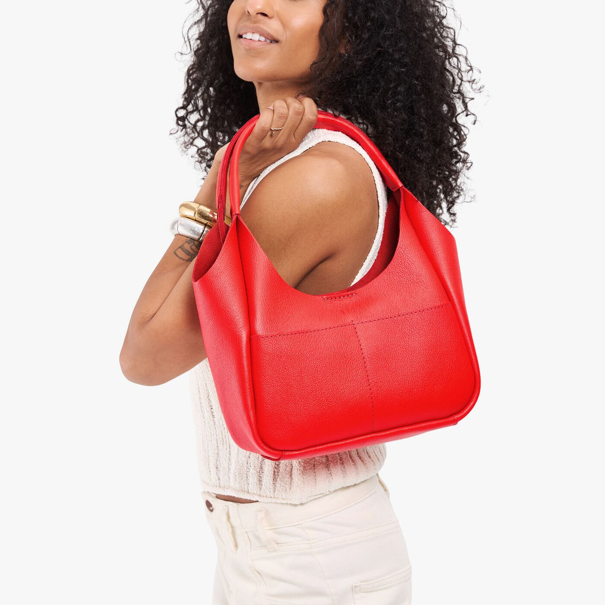 Candy*Medium | Model holding a u-shaped, flat-bottomed leather shoulder bag with two outside pockets