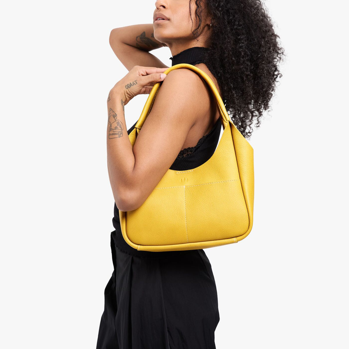 Pomello*Medium | Model carrying a u-shaped, flat-bottomed leather shoulder bag with two outside pockets