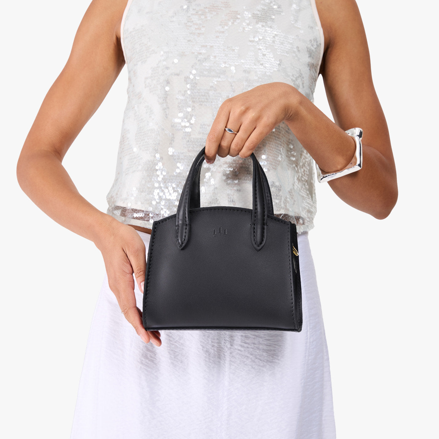 Black*Mini | Model holding small leather tote bag with handles, adjustable crossbody strap, and one back pocket