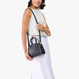 Black Mini | Model carrying small leather tote bag with handles, adjustable crossbody strap, and one back pocket
