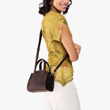 Moose Mini | Model carrying small leather tote bag with handles, adjustable crossbody strap, and one back pocket