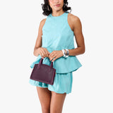 Plum Mini | Model carrying small leather tote bag with handles, adjustable crossbody strap, and one back pocket