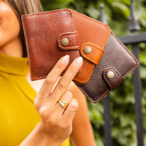 Person holding three Mini Bifold Wallets in outdoor setting. featured image