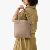 Stone | Model holding leather tote bag with riveted straps and exterior key loop 