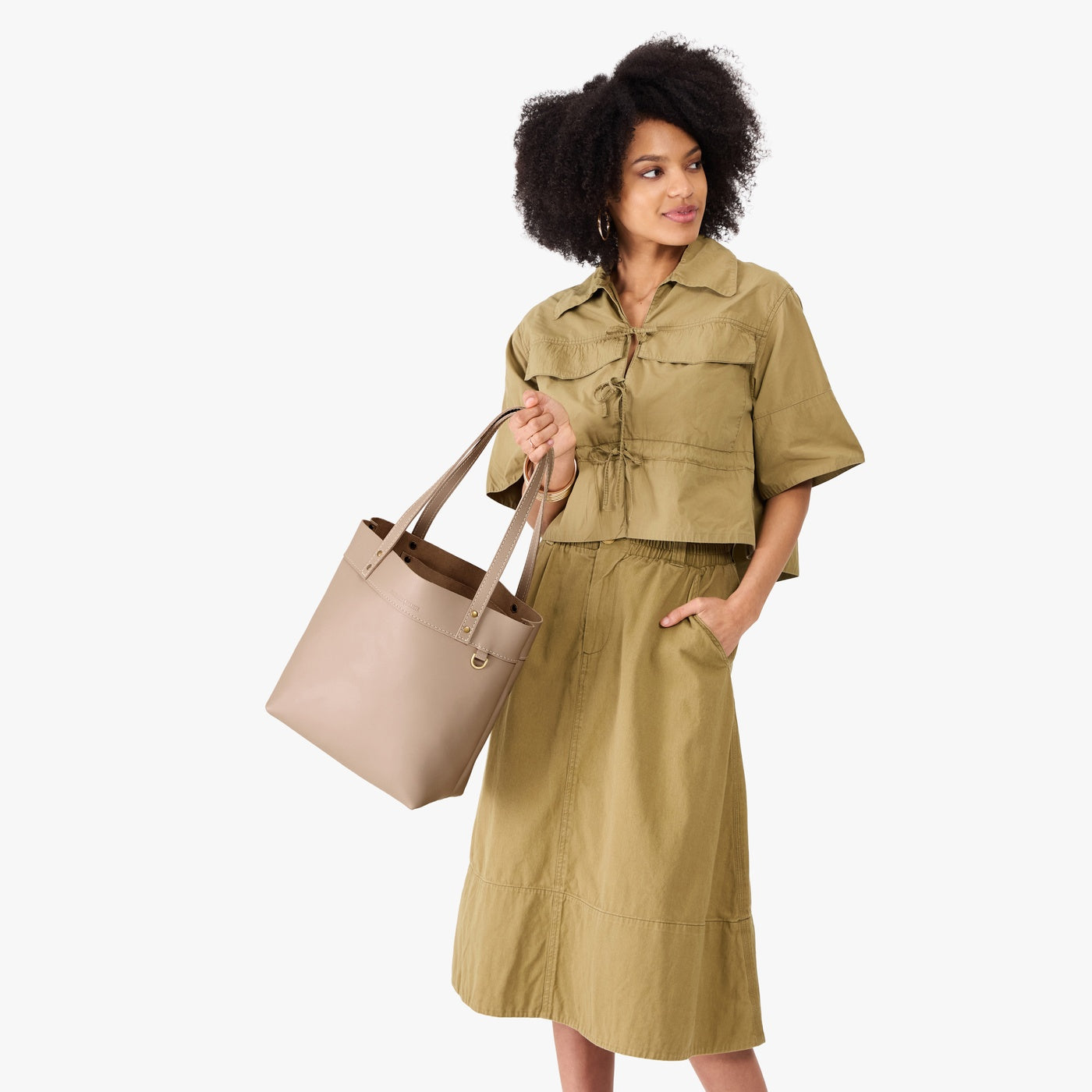 Stone*Medium*Classic | Model holding leather tote bag with riveted straps and exterior key loop 