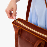 Nutmeg Medium Zipper | Model wearing leather tote bag with riveted straps and exterior key loop