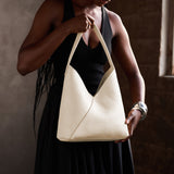 Pebbled Bone Large | Model holding mid-size shoulder bag with magnetic snap closure