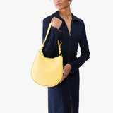Butter Bliss Medium | Model carrying round leather purse with adjustable shoulder strap