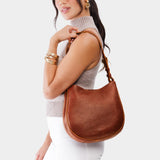 Nutmeg Medium | Woman wearing rounded shoulder bag with adjustable strap on a white background