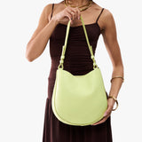 Shadow Lime Medium | Model holding round leather purse with adjustable shoulder strap