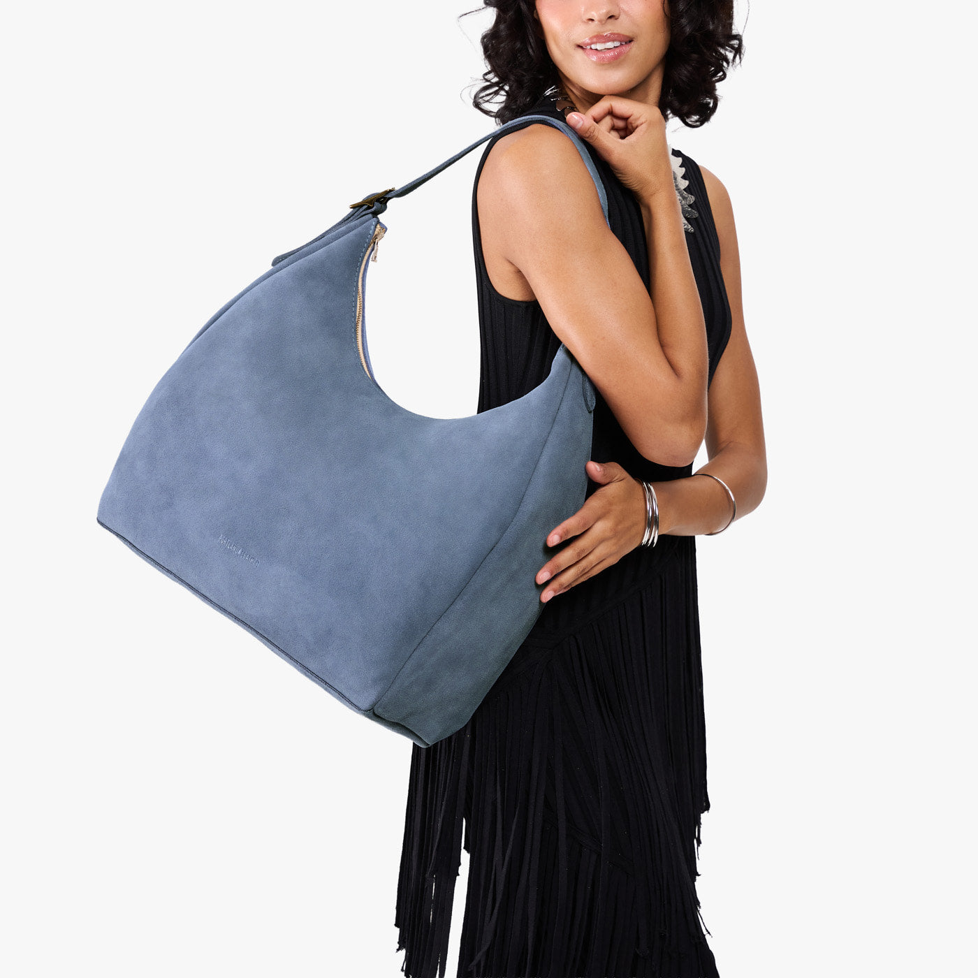 Denim*Oversized | Model holding u-shaped, flat-bottomed leather shoulder bag with adjustable strap