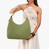 Laurel Oversized | Model holding u-shaped, flat-bottomed leather shoulder bag with adjustable strap