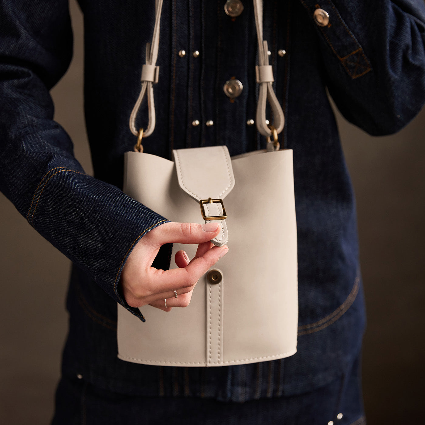 Dragon Bone | Model wearing leather bucket shoulder bag with adjustable strap and magnetic closure 