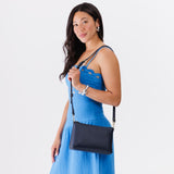 Night Owl Classic | A Model holding a zip top crossbody bag with detachable strap