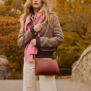 A model outdoors carrying a leather shoulder bag
