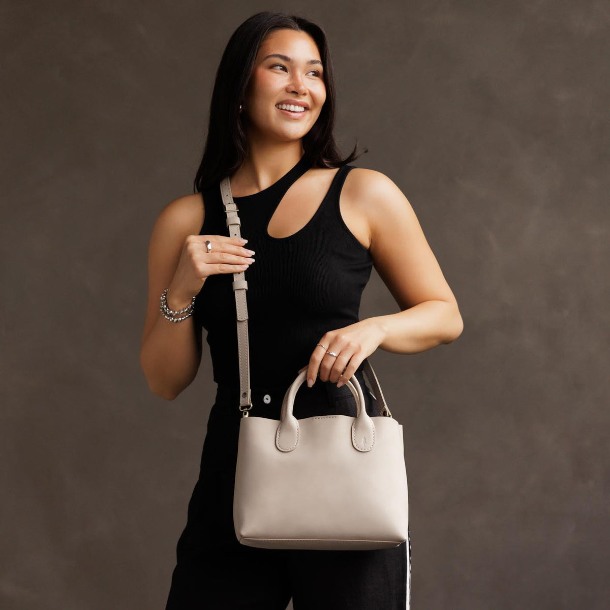 Dragon Bone*Large | Model holding mid-size tote purse with  structured leather handles and crossbody strap