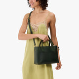 Evergreen Large | Model wearing a mid-size tote purse with  structured leather handles and crossbody strap
