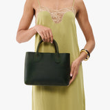 Evergreen Large | Model wearing a mid-size tote purse with  structured leather handles and crossbody strap