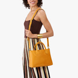 Sunshine Large | Model wearing a mid-size tote purse with  structured leather handles and crossbody strap