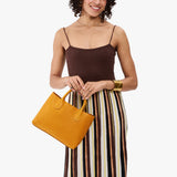Sunshine Large | Model wearing a mid-size tote purse with  structured leather handles and crossbody strap