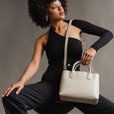 Bone Large | Model holding mid-size tote purse with  structured leather handles and crossbody strap