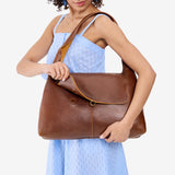 Asheville Large | A model holding a slouchy triangle shaped shoulder bag with a flap