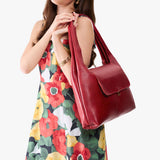 Chili Red Large | A model holding a slouchy triangle shaped shoulder bag with a flap