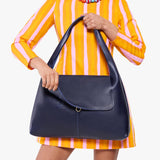 Cobalt Large | A model holding a slouchy triangle shaped shoulder bag with a flap