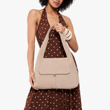 Taupe Medium | A model holding a slouchy triangle shaped shoulder bag with a flap