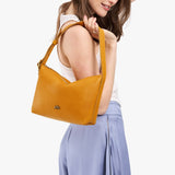Sunshine Small | Model holding a Slouchy Shoulder Bag that has a zipper opening and three metal tree emblems