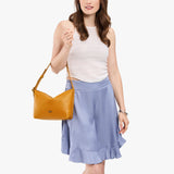 Sunshine Small | Model holding a Slouchy Shoulder Bag that has a zipper opening and three metal tree emblems