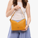 Sunshine Small | Model holding a Slouchy Shoulder Bag that has a zipper opening and three metal tree emblems