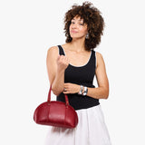 Chili Red Small | Model holding a half circle crossbody bag with handles and removable crossbody strap 