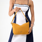 Dijon Small | Model holding a Slouchy Shoulder Bag that has a zipper opening and three metal tree emblems