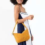 Dijon Small | Model holding a Slouchy Shoulder Bag that has a zipper opening and three metal tree emblems