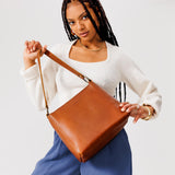 Honey Small | Model holding triangular shoulder bag with antiqued brass finished hardware