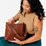 Nutmeg Classic | Model holding triangular shoulder bag with antiqued brass finished hardware